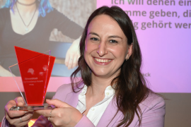 Foto einer Preisträgerin, die den Young Excellence Award in die Kamera präsentiert.