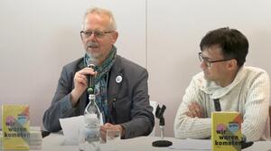 Zwei Männer sitzen nebeneinander an einem Tisch. Der Mann auf der linken Seite hält in seiner rechten Hand ein Mikrofon und spricht zum Publikum. Der Mann auf der rechten Seite schaut zum anderen Mann. Beide tragen eine Brille. Auf dem Tisch stehen zwei Bücher mit dem Titel "wir waren kometen".