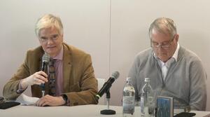 Zwei Männer sitzen nebeneinander an einem Tisch. Der Mann auf der linken Seite hält in seiner rechten Hand ein Mikrofon und spricht zum Publikum. Der Mann auf der rechten Seite trägt eine Brille und schaut auf den Tisch. Auf dem Tisch steht ein Buch mit dem Titel "Werther trifft auf Winnetou. Über Goethe und Karl May".