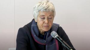 Eine Frau sitzt an einem Tisch und spricht in ein Mikrofon.