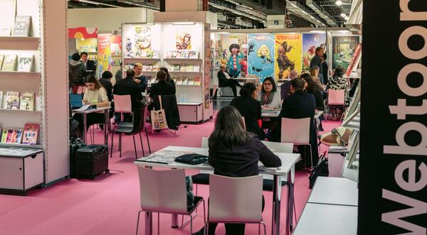 Menschen an Tischen im Ausstellungsareal Webtoon Area