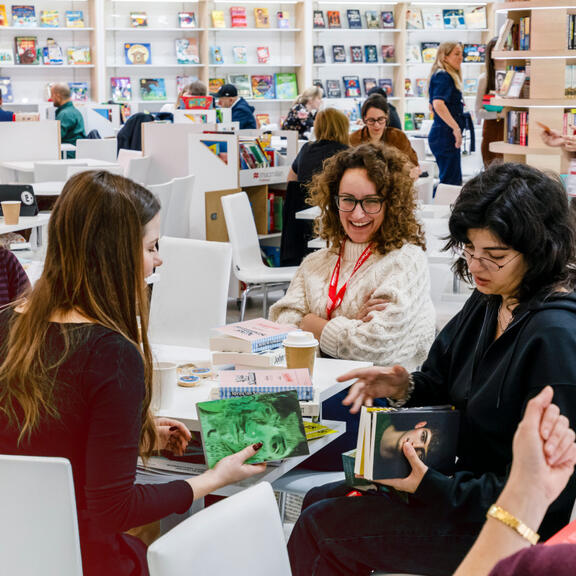 Vier Personen beschäftigen sich an einem Tisch mit Büchern. 