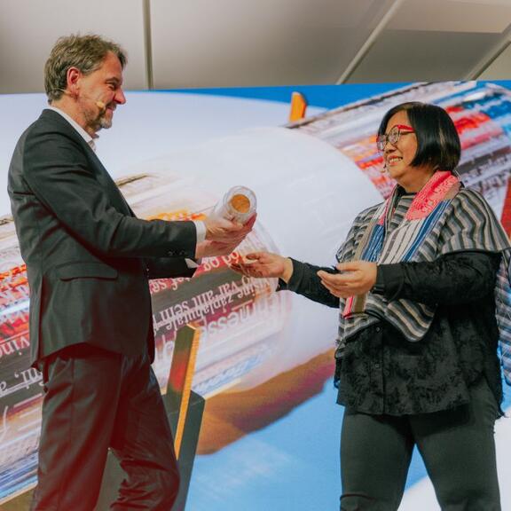 Die Vertreterin des philippinischen Ehrengastes übergibt die Gastrolle an den Vertreter Tschechiens