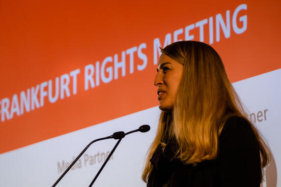 Sprecherin steht vor zwei Mikrofonen. 