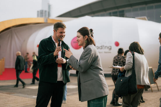 Mann und Frau mit Smartphone vor Pavilion